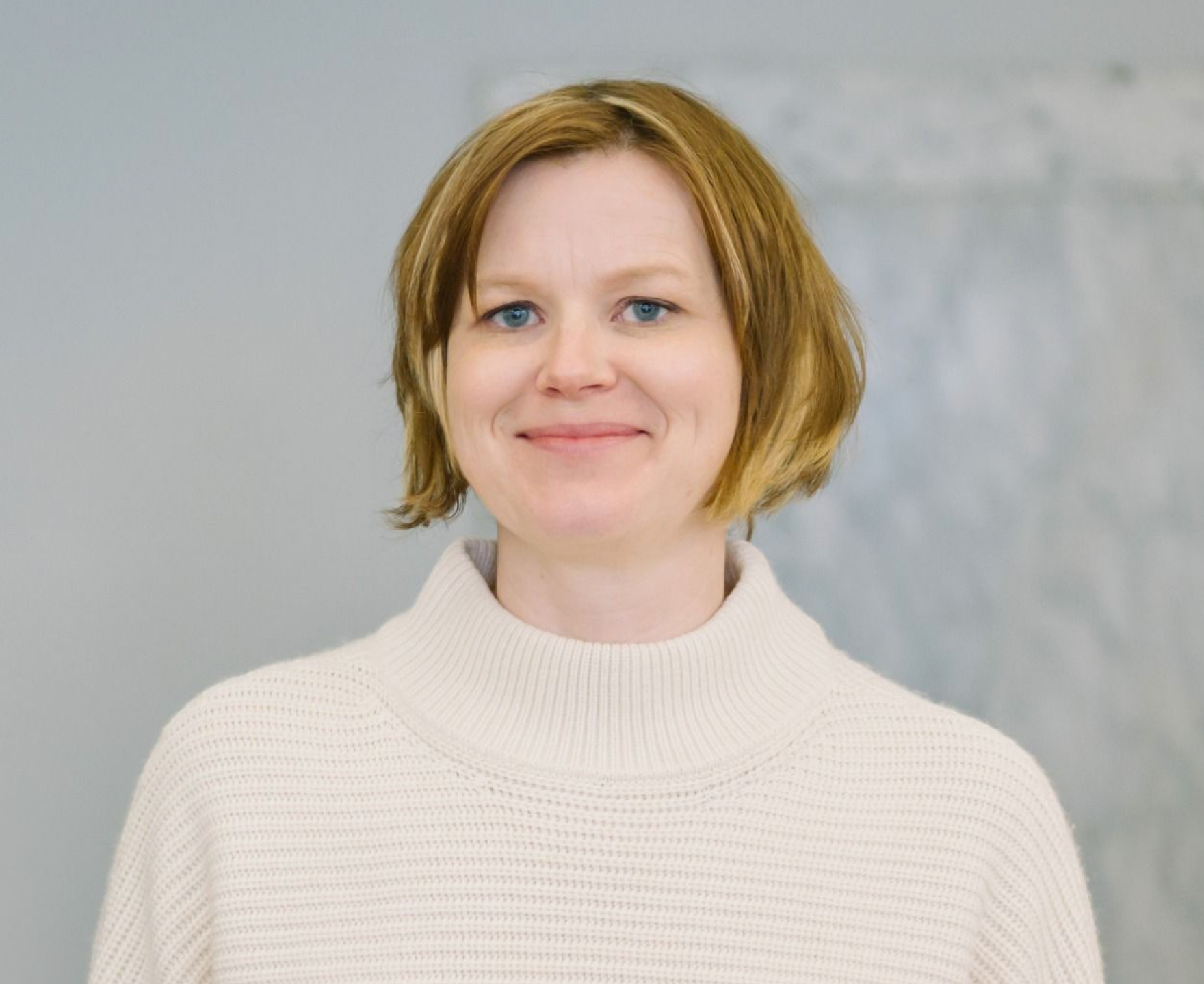 Person wearing a light pink sweater against a plain background